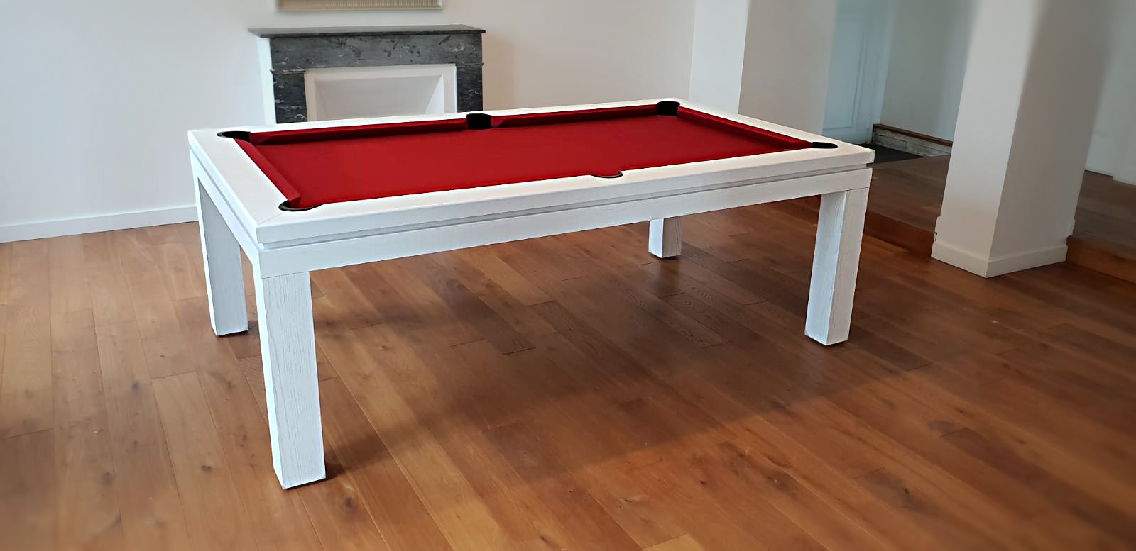 Le tissu de jeu rouge — posé sur ce billard NEW TENDANCE T <tout de blanc — attise le plaisir du jeu.